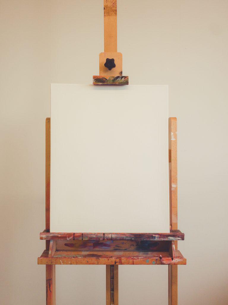 Blank canvas sitting on a paint splattered easel
