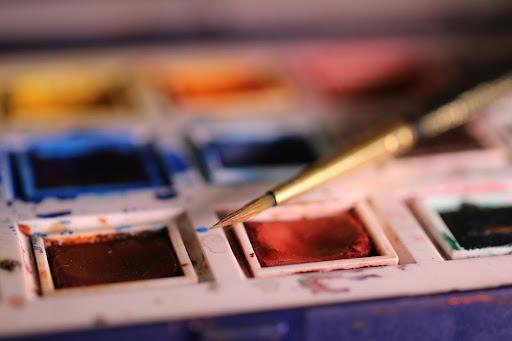 Paint brush sat on a watercolour palette (Nick Collins on Unsplash)